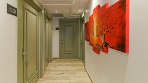 A hallway with doors labeled 1001 and 1003, a tiled floor, and a red abstract painting on the wall. - Rise Inn  (Istanbul)