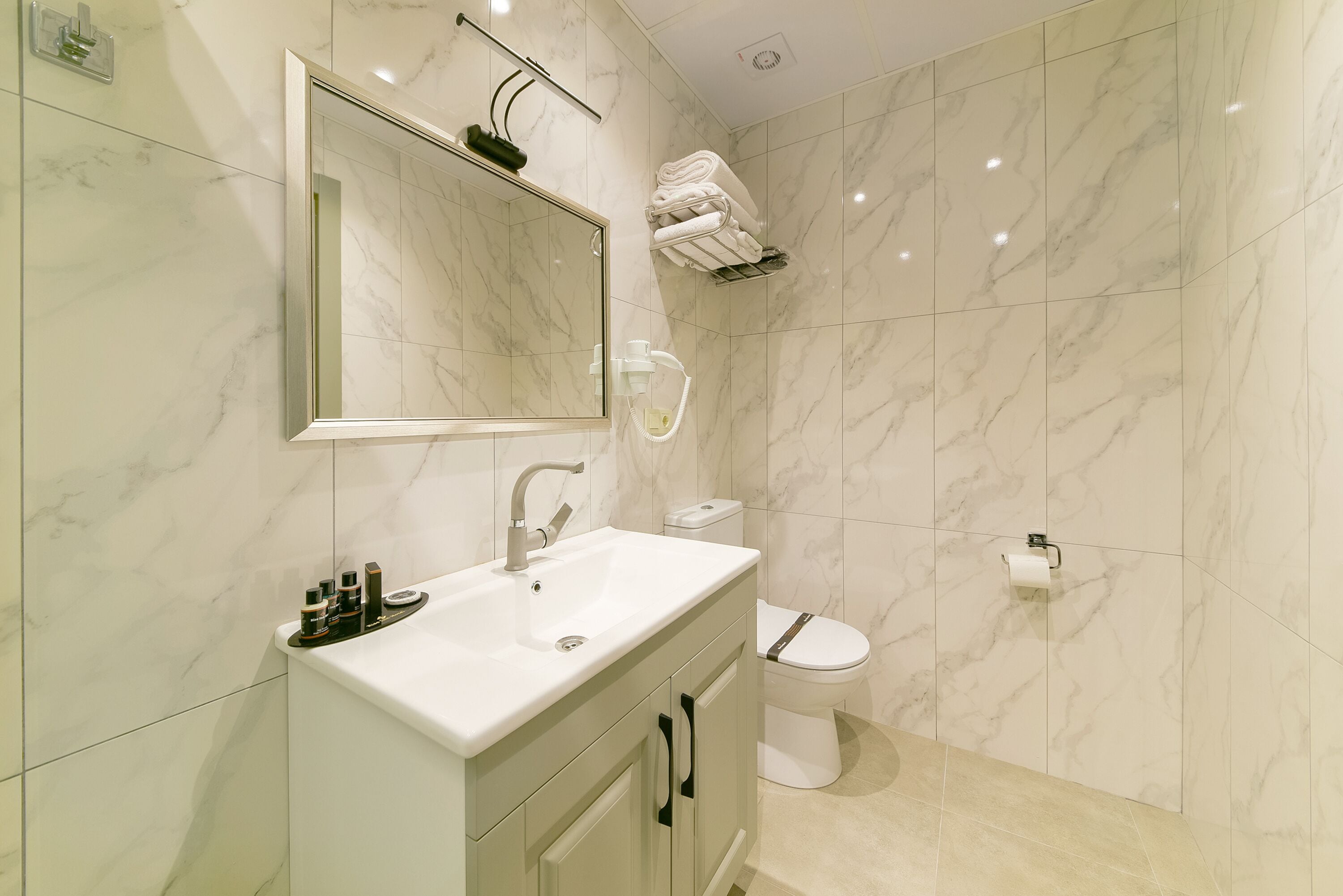 Ein modernes Badezimmer mit einem Marmorwaschbecken, einer Toilette und einem Handtuchhalter.