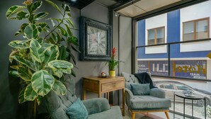 A modern office space with a large window, a potted plant, a framed clock, and a grey sofa. - Rise Inn  (Istanbul)