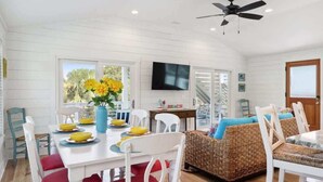 A dining area with a white table, red chairs, and a wicker sofa with blue cushions.