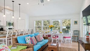 A spacious living area with a blue sofa, wicker furniture, and a dining table with chairs.
