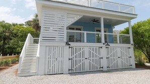 A two-story building with a covered upper deck, a staircase, and a gated entrance.