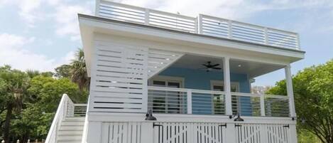A two-story building with a covered upper deck, a staircase, and a gated entrance.