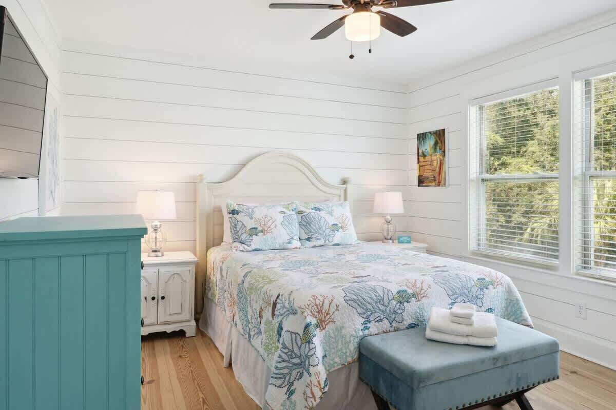 A bedroom with a bed, bedside tables, a ceiling fan, and a window with blinds.