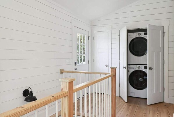 Une buanderie équipée d’un lave-linge, avec une rambarde en bois et une fenêtre.