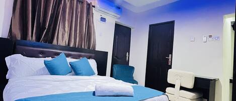 A modern bedroom with a large bed, a desk, and a ceiling light fixture.