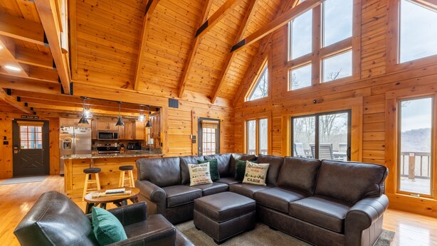 Interior de cabine espaçoso, com um amplo sofá modular, uma poltrona de couro e um espaço bar.