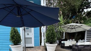 A pool area with a brick pool, outdoor seating, and umbrellas.
