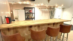 A bar area with a wooden counter and four brown bar stools. - The Barndominium - Lots of Space! (Butternut)