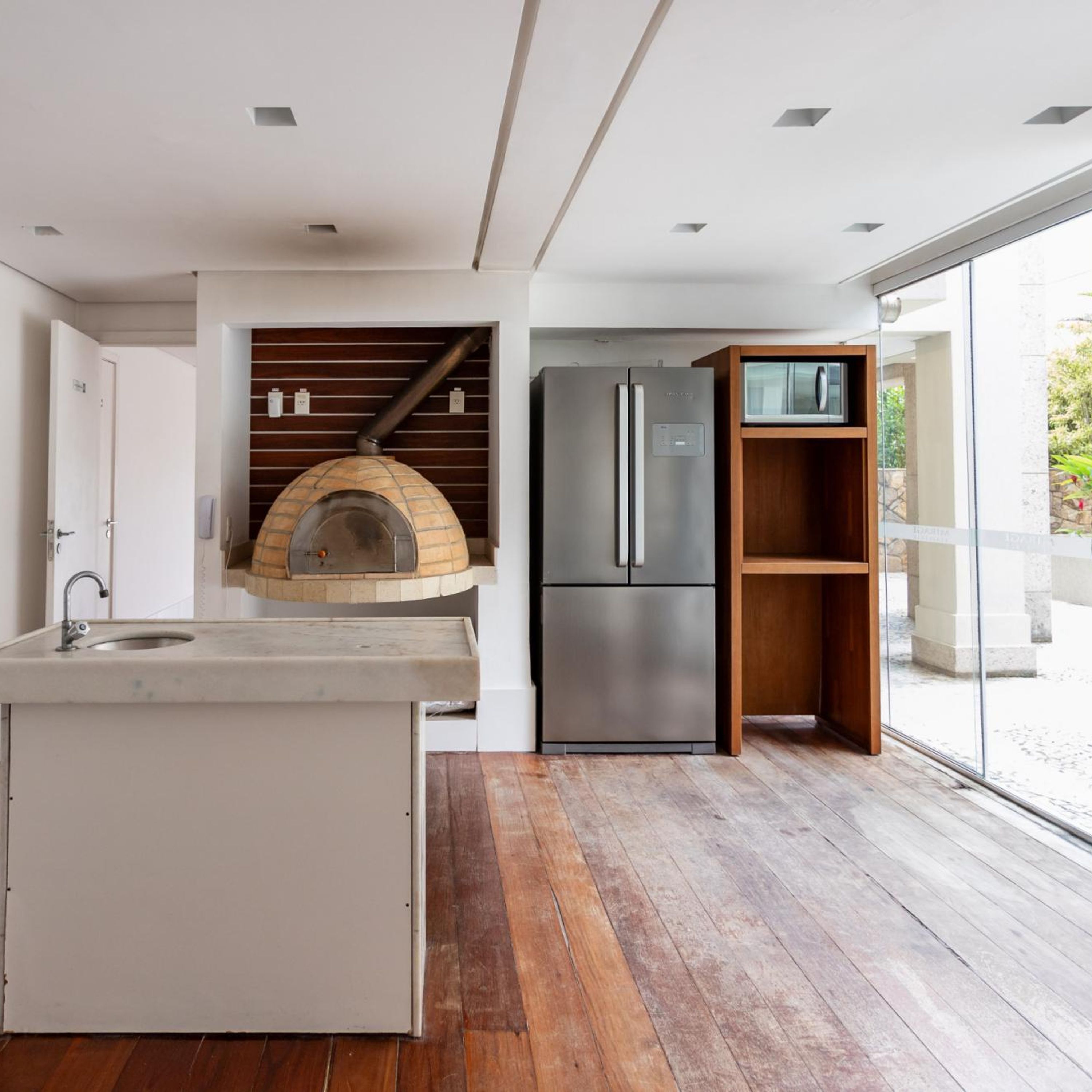Una cocina moderna con horno empotrado, refrigerador de acero inoxidable y estante de madera.