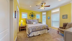 A bedroom with a bed, a nightstand, a lamp, a ceiling fan, and a chair. - Absolute Paradise: 3 BR, 2 BA House in Crystal Beach , Sleeps 14 (Bolivar Peninsula)