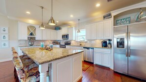 A modern kitchen with white cabinetry, granite countertops, stainless steel appliances, and pendant lighting. - Absolute Paradise: 3 BR, 2 BA House in Crystal Beach , Sleeps 14 (Bolivar Peninsula)