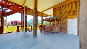 Un espace extérieur abrité, avec une table et des chaises en bois, une balançoire et une porte.