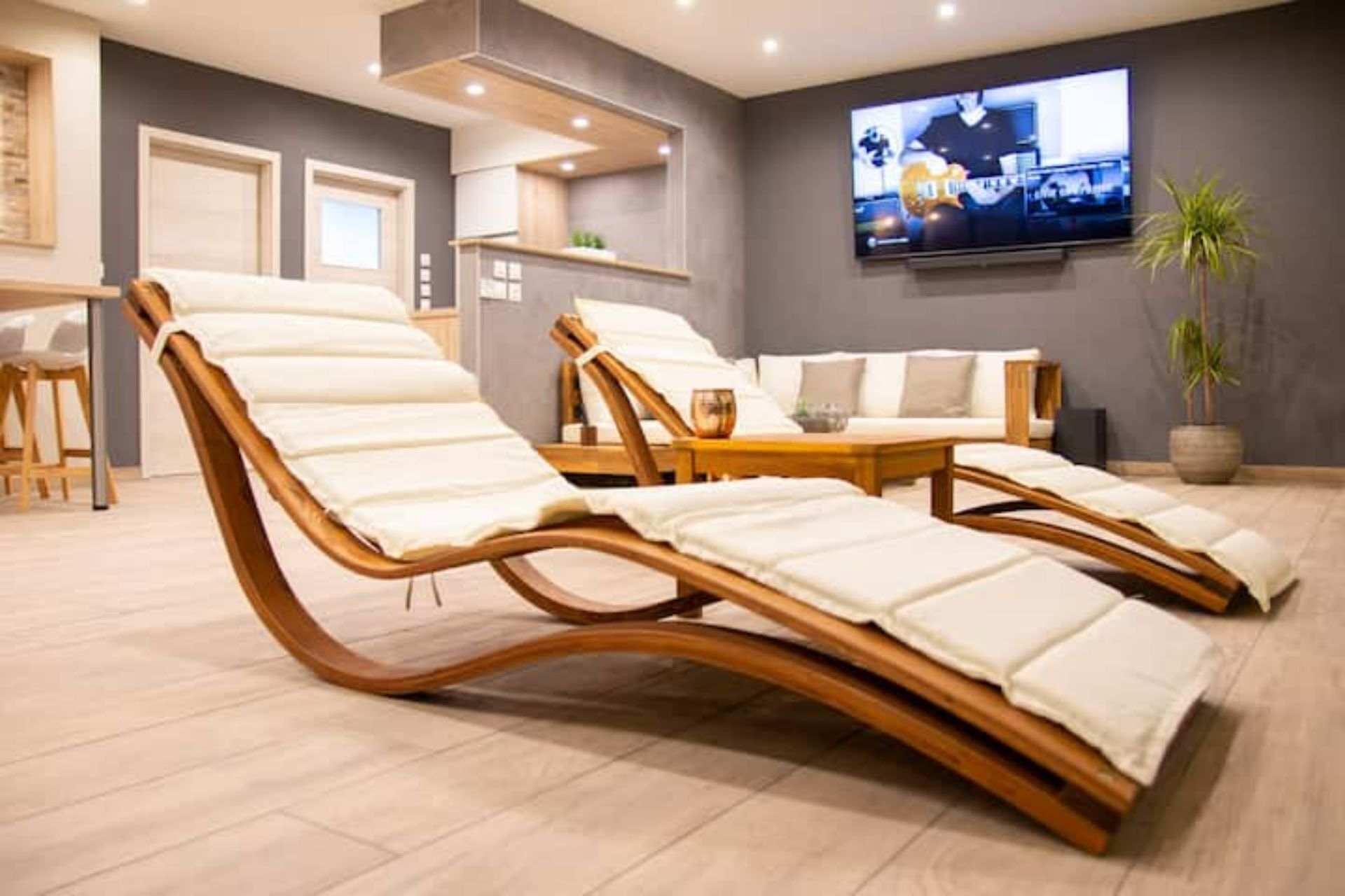 Ein modernes Wohnzimmer mit großem Flachbildfernseher, einem Holztisch und einer Couch.