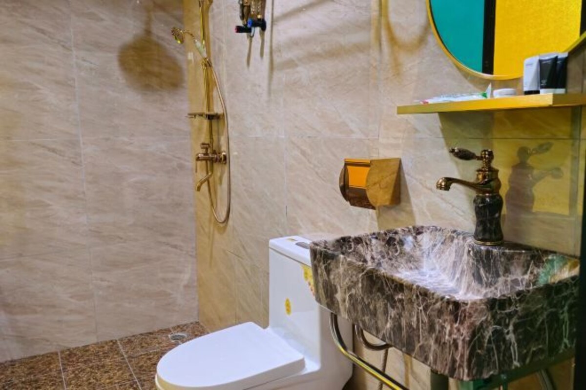 A bathroom with a marble sink, a toilet, and a shower.