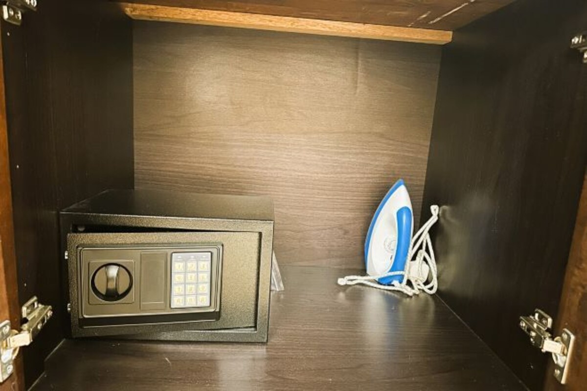 A dark wooden cabinet with a microwave and an iron.