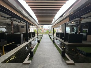 A covered walkway with seating areas on both sides, a central water feature, and a view of the cityscape in the background. - THE CENTURY BOUTIQUE HOTEL (George Town)
