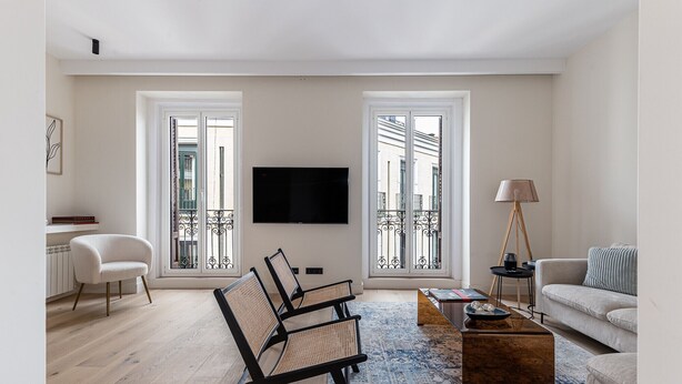 A living room with a sofa, two armchairs, a coffee table, a TV, and a floor lamp.