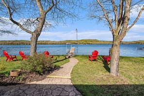 A lakeside seating area with red chairs and a pathway leading to a dock. - Welcome to the Loon Lodge on Intermediate Lake! (Bellaire)