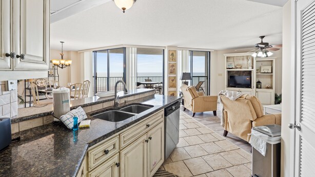A spacious kitchen with granite countertops, a dishwasher, and a dining area with a table and chairs. - Gulf-Front at Aquavista w/ Pool, Hot Tub & Sunset Views (Panama City Beach)