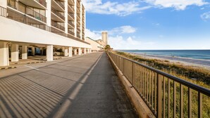 A long, straight pathway leading to a beach, flanked by a high-rise building with balconies and a railing. - Gulf-Front at Aquavista w/ Pool, Hot Tub & Sunset Views (Panama City Beach)
