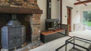A rustic interior with a brick fireplace, a wooden bench, and a glass table. - Idyllic Home in Picturesque Village of Wraysbury - Pass the Keys (Wraysbury)
