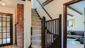 A staircase with wooden railings leading to a living area with a gray sofa and a coffee table. - Idyllic Home in Picturesque Village of Wraysbury - Pass the Keys (Wraysbury)