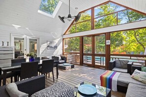 A covered outdoor deck with seating, a dining area, and a view of a pool.