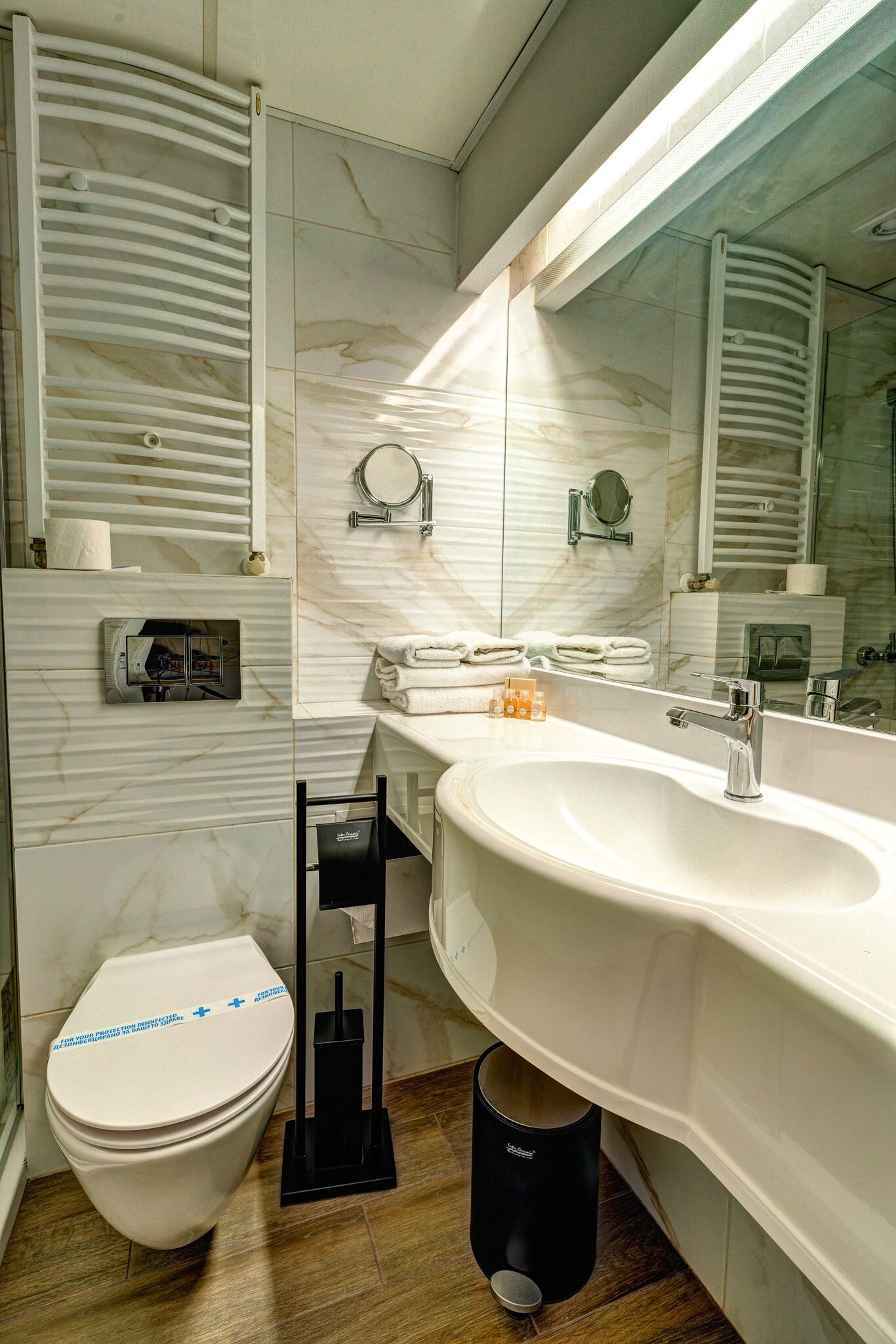 Une salle de bain moderne avec un grand miroir, un lavabo blanc et des toilettes.