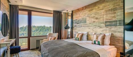 Una habitación de hotel moderna con una cama grande, un escritorio y vistas al bosque.