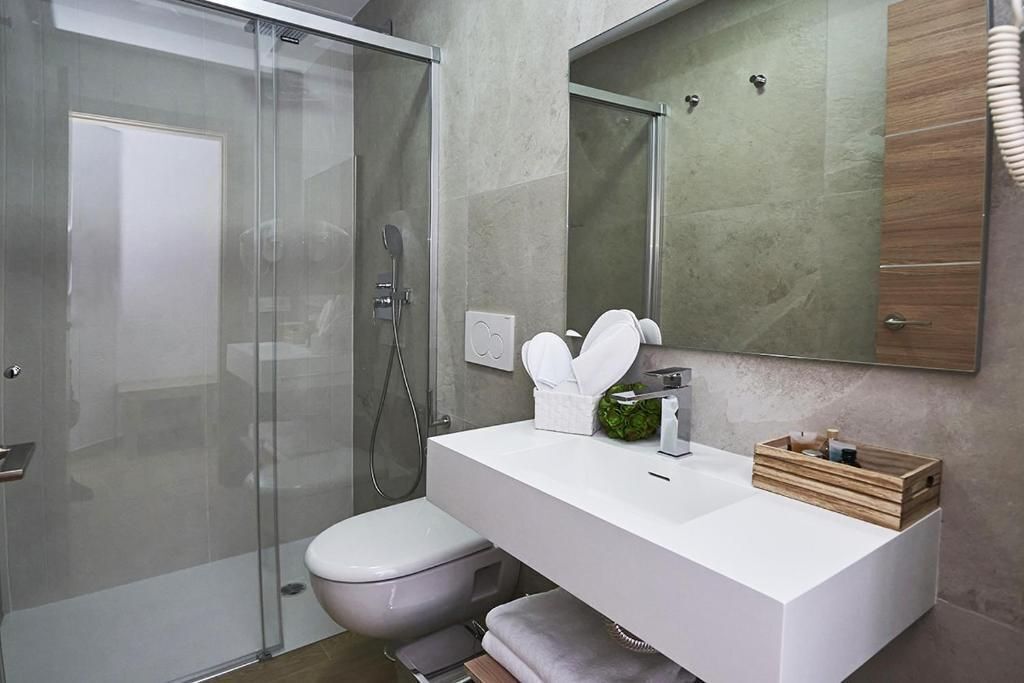A modern bathroom with a glass shower enclosure, a white sink, and a large mirror.