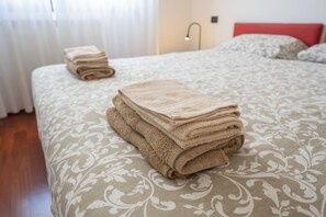 Un lit bien fait, avec une couvre-lit à motifs et une pile de serviettes pliées.
