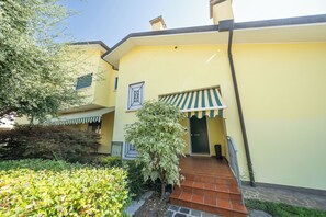 A yellow building with a green awning, a brick entrance, and a small garden area. - Elegant apartment with garden and parking spot, close to Airport and Venice (Venezia)