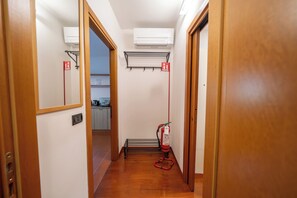 A narrow hallway with wooden doors, a fire extinguisher, and a hand dryer on the wall.