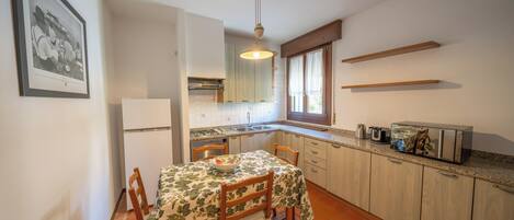 Una cocina compacta con una mesa de comedor, sillas, un refrigerador, un microondas y una tostadora.