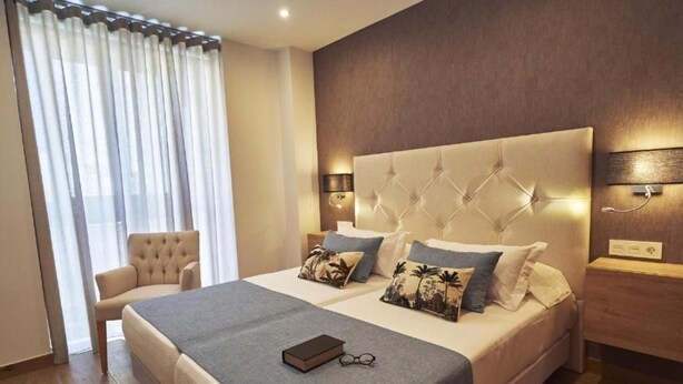 Una habitación de hotel moderna con una cama grande, una silla y una mesita de noche.