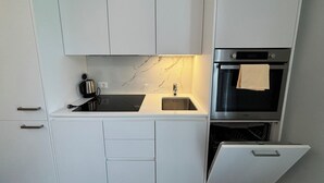 Eine kompakte Küche mit weißen Schränken, einer schwarzen Arbeitsplatte, einem eingebauten Backofen und einem Geschirrspüler.