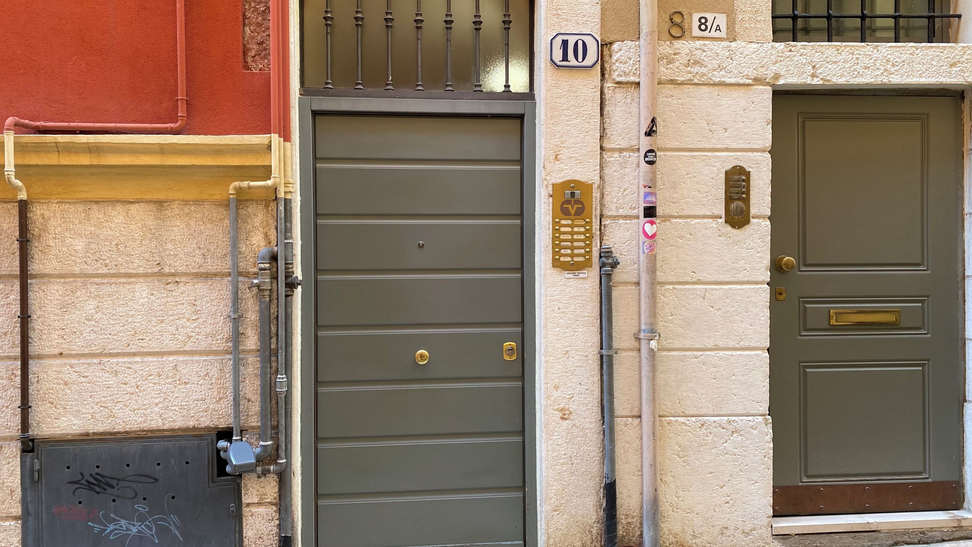 Une façade d’immeuble avec une porte grise, une boîte aux lettres et une plaque portant le numéro « 10 ».