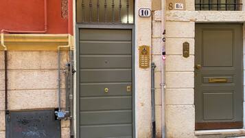 Une façade d’immeuble avec une porte grise, une boîte aux lettres et une plaque portant le numéro « 10 ».