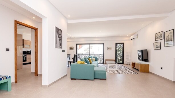 A spacious living area with a sofa set, a TV, and artwork on the walls. - Paul Verlaine  (La Marsa)