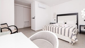 A modern hotel room with a large bed, a dining table, and a chair. - Paul Verlaine  (La Marsa)