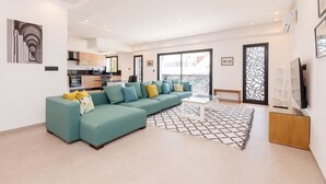 A modern living room with a teal sofa, a coffee table, and a patterned rug. - Paul Verlaine  (La Marsa)