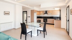 A modern kitchen with a central island, a dining area with a glass table, and a visible laundry area. - Paul Verlaine  (La Marsa)