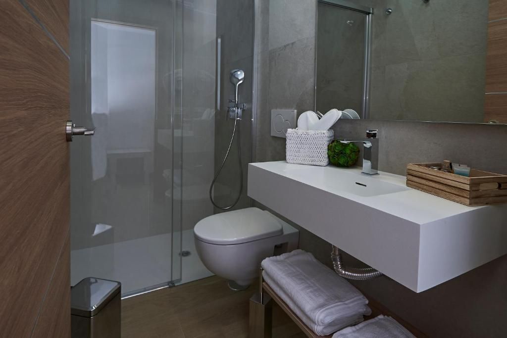 A modern bathroom with a glass shower enclosure, a white sink, and a toilet.