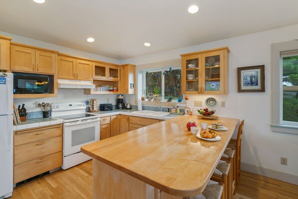 A modern kitchen with wooden cabinets, a central island, and a large window.