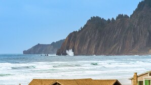 A coastal view with a house in the foreground and a rocky cliff in the background.