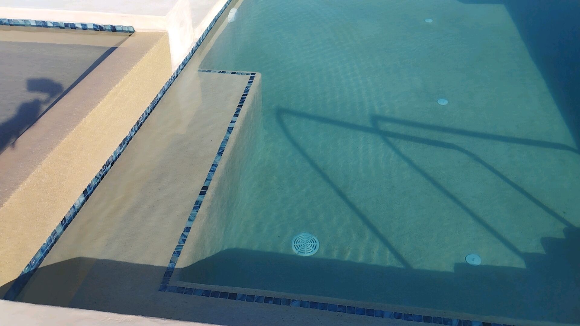 Vista clara de una piscina con borde de azulejos y desagüe central.