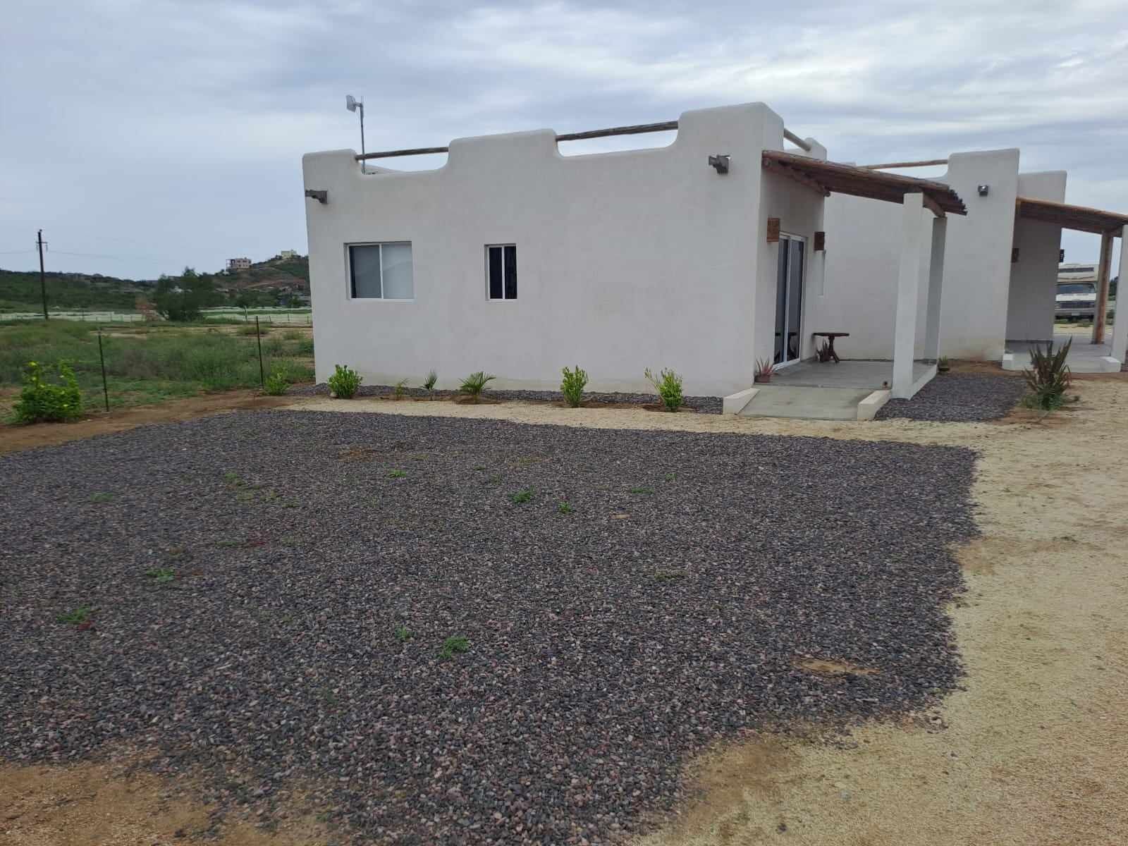A modern, single-story building with a flat roof, a small porch, and a gravel driveway.