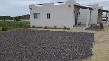 A modern, single-story building with a flat roof, a small porch, and a gravel driveway.