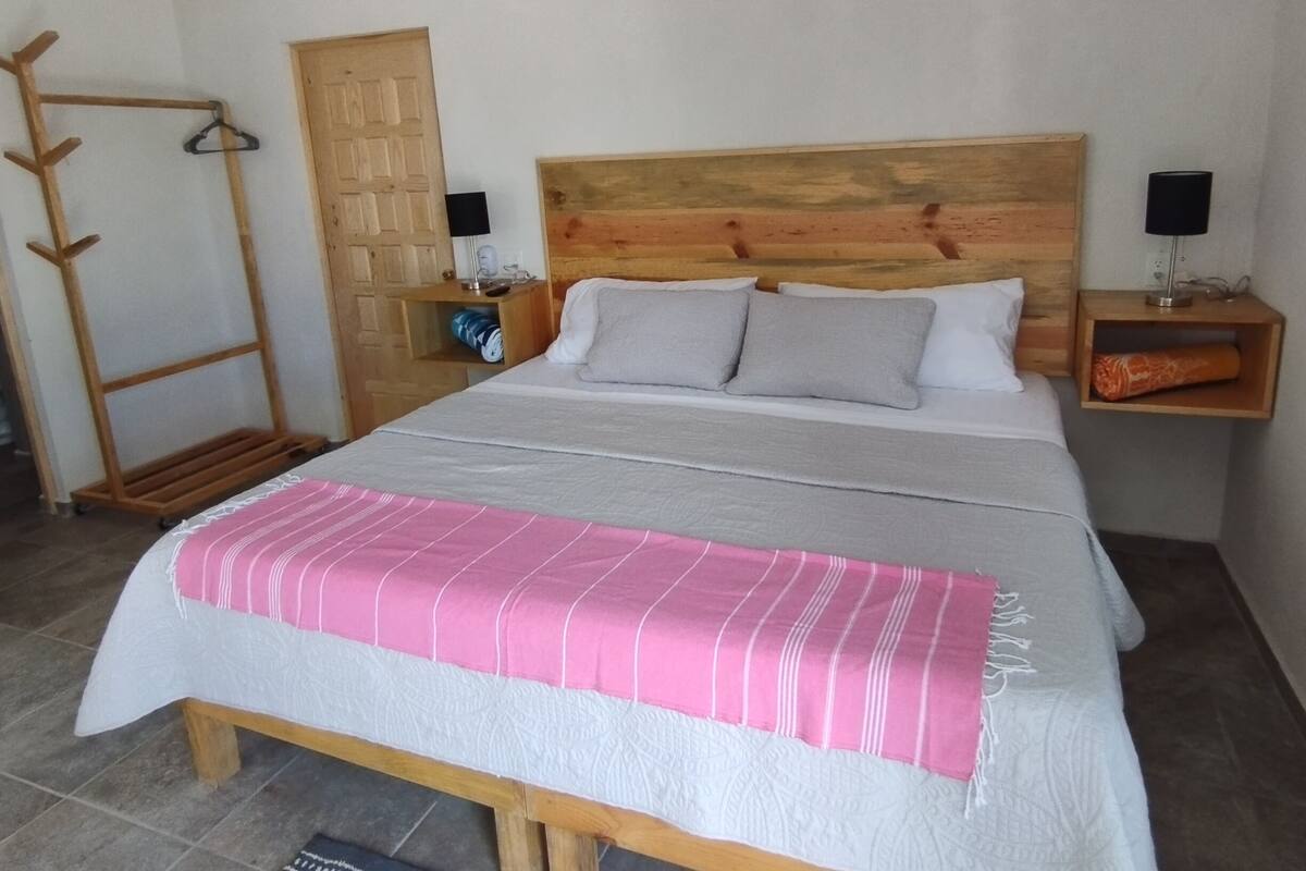 Ein Schlafzimmer mit einem hölzernen Bettgestell, einem Nachttisch aus Holz, einem Schrank aus Holz und einem Wäscheständer.